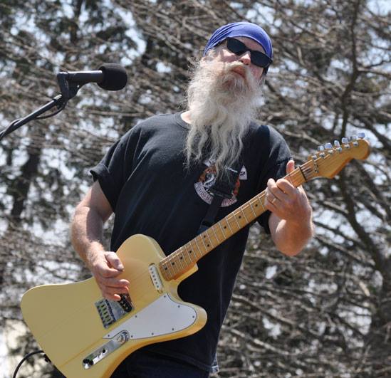 A person with a long beard playing a guitar

Description automatically generated